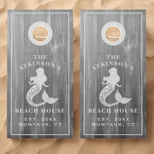 Pair Of Gray Wooden Cornhole Boards With A Mermaid Design, The Atkinson'S Beach House Name, And Establishment Year.