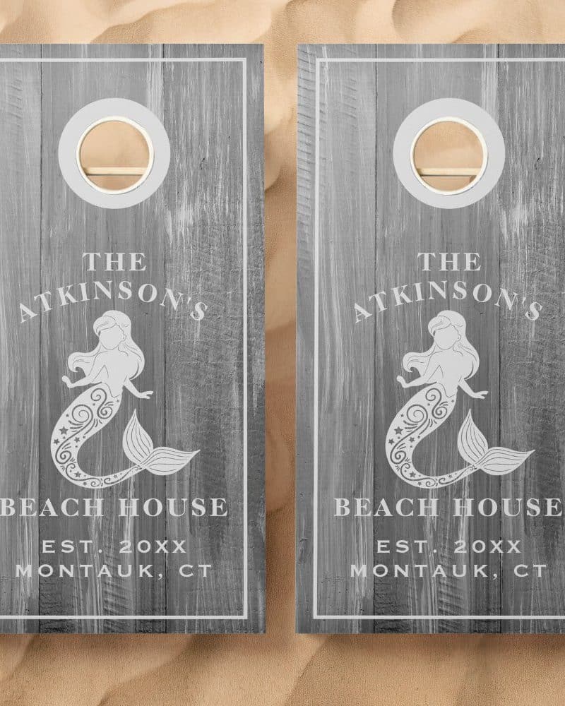 Pair of gray wooden cornhole boards with a mermaid design, the Atkinson's Beach House name, and establishment year.