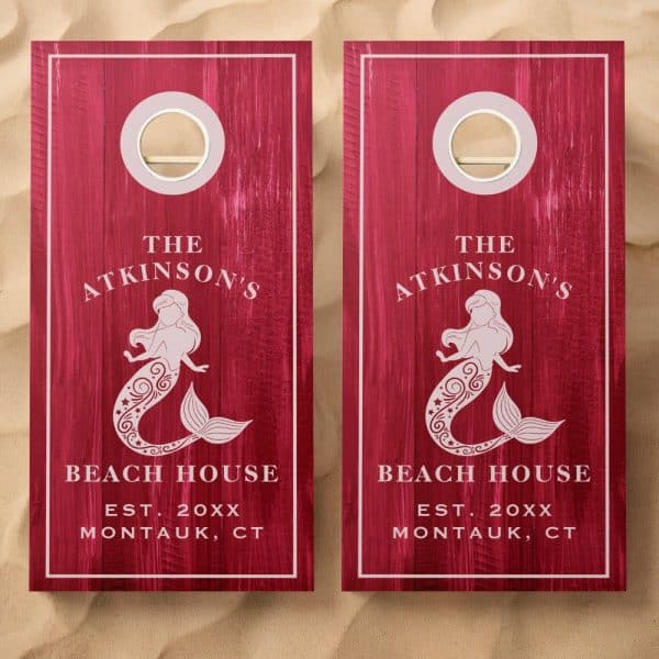 Pair Of Dark Red Wooden Cornhole Boards, Each Featuring A Mermaid Design, The Atkinsons Beach House Text, And Establishment Year.