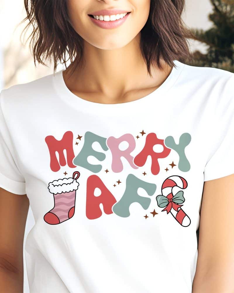 Woman wearing a white t-shirt with a Christmas design that says Merry AF. A stocking and candy cane are included in the design.