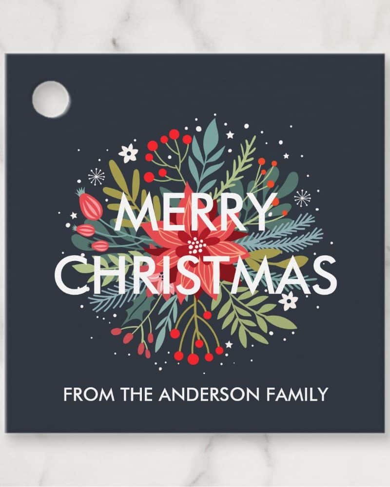 Dark blue square Christmas gift tag with a floral wreath design, "Merry Christmas" in white lettering, and "From the Anderson Family" at the bottom.