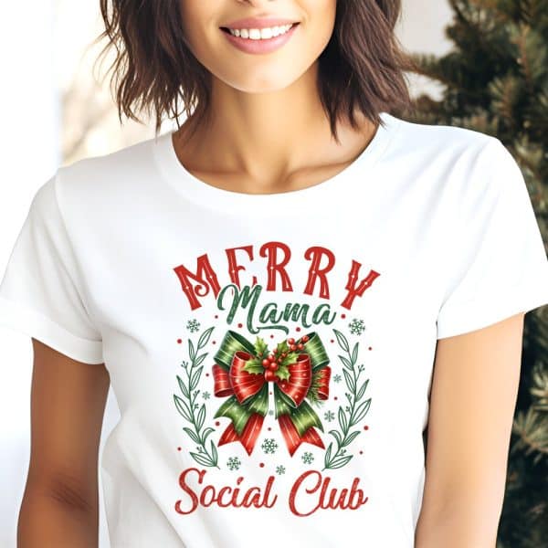 White T-Shirt With A Christmas Design Featuring A Red And Green Bow, Snowflakes, And The Text Merry Mama Social Club.