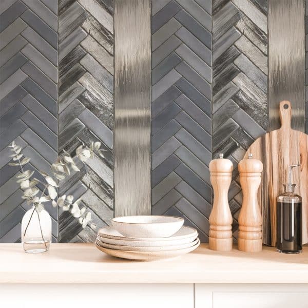 Gray And Silver Herringbone Tile Backsplash With Stacked Dishes And Kitchen Utensils.