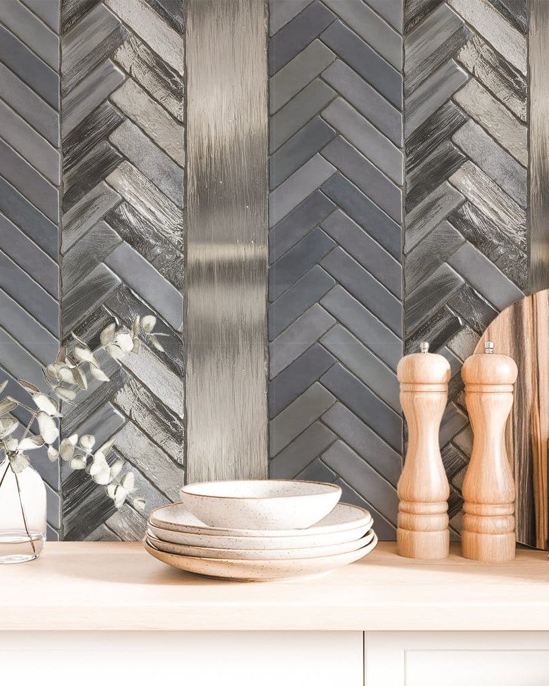 Gray and silver herringbone tile backsplash with stacked dishes and kitchen utensils.