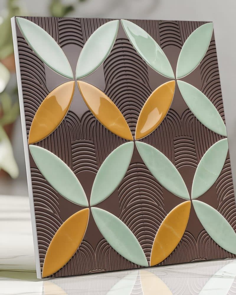 Square tile with a repeating pattern of overlapping, stylized flower shapes in shades of green and gold on a brown background.