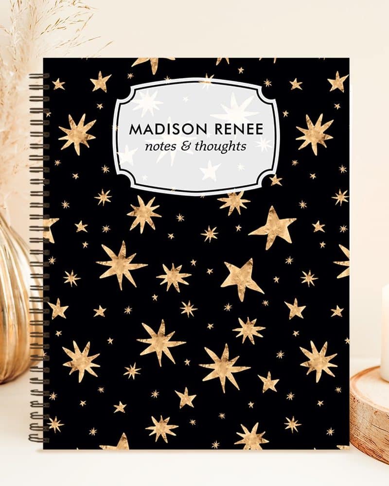 Black spiral notebook with a gold star pattern and personalized name, Madison Renee, on the cover.