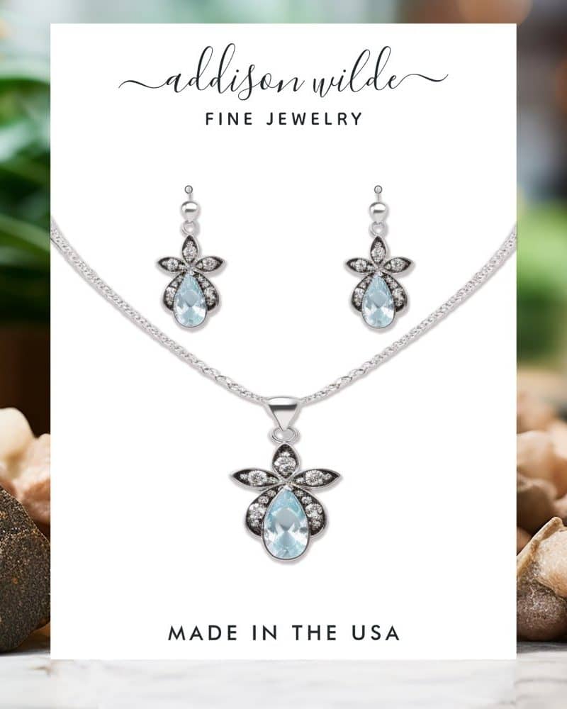 Silver necklace and earring set with light blue teardrop pendants and floral accents. Made in the USA.
