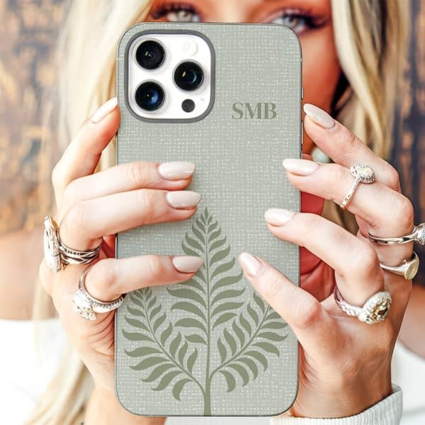 A Woman'S Hands Hold A Light Beige Iphone Case Featuring A Fern Design And Initials Smb.