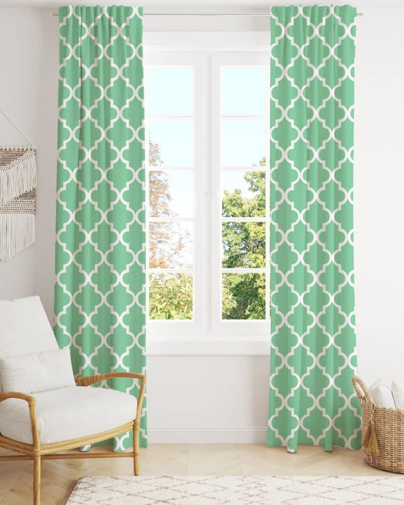 Light green curtains with a quatrefoil pattern hang in front of a window.