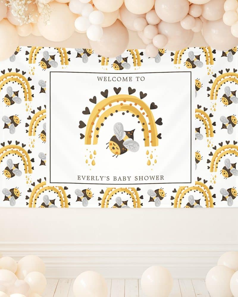 Baby shower banner featuring a bee flying under a rainbow decorated with hearts. The banner also includes the baby's name and "Welcome to Everly's Baby Shower."