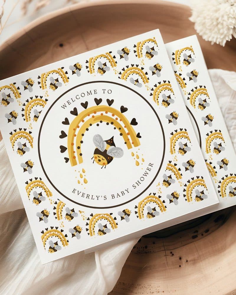 Baby shower invitation featuring a bee under a rainbow.