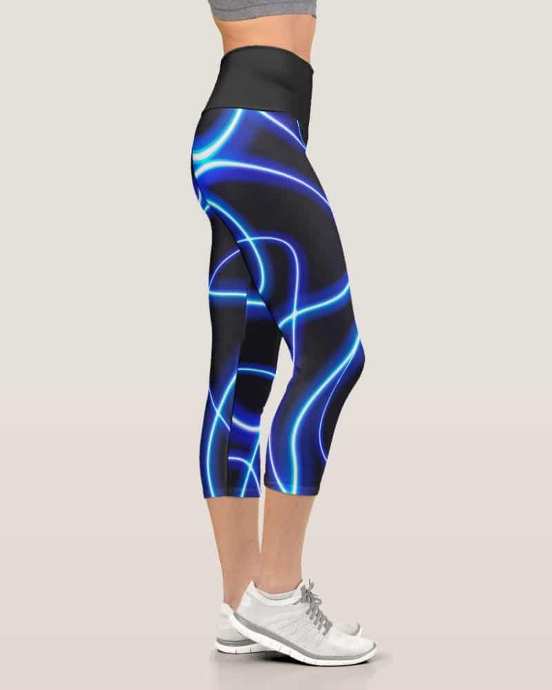Womens cropped leggings with a neon blue light pattern on a dark background.