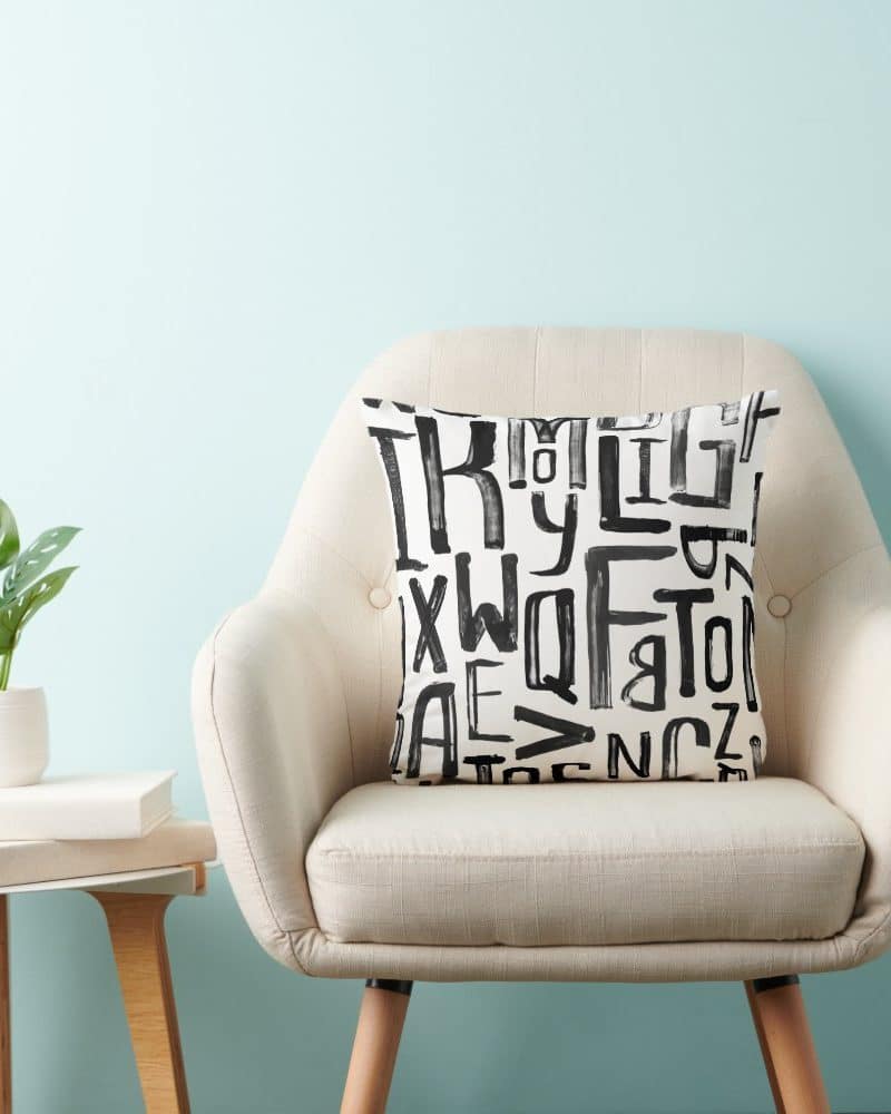 Beige armchair with a black and white alphabet pillow.