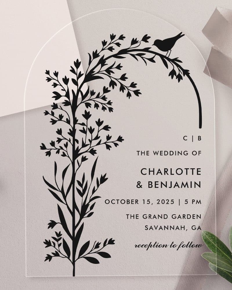 Clear acrylic wedding invitation with black floral illustration and bird, announcing Charlotte and Benjamin's wedding.
