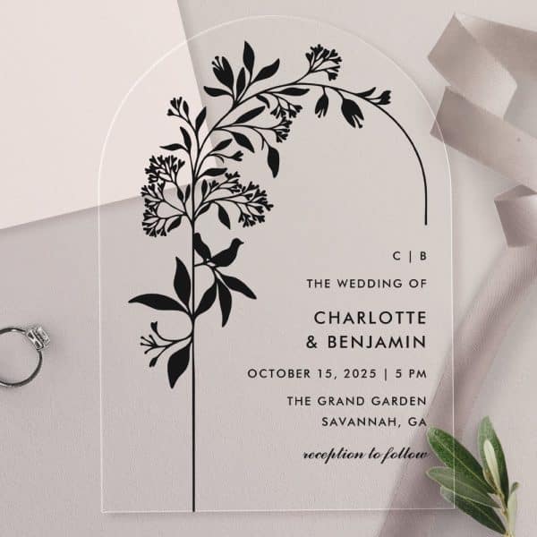 Arch-Shaped Clear Acrylic Wedding Invitation With A Black Floral Design And Bird. The Invitation Features The Couple'S Names And Wedding Details.