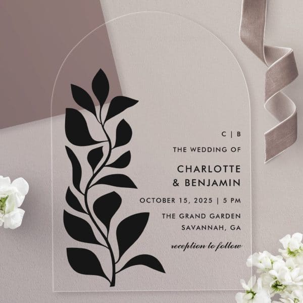 Clear Acrylic Wedding Invitation With A Black Floral Design And Wedding Details For Charlotte And Benjamin.