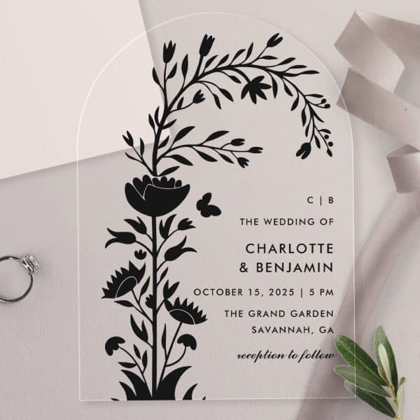 Arch-Shaped Clear Acrylic Wedding Invitation With A Black Floral Design And Wedding Details.