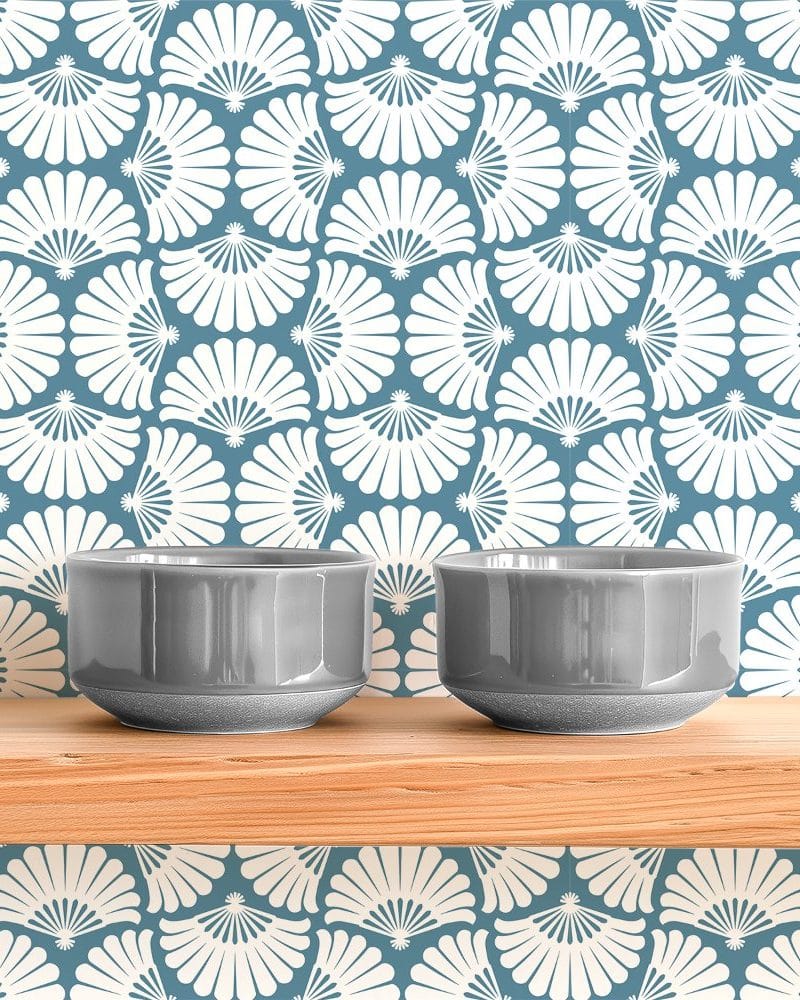 Two gray bowls sit on a wooden shelf against a wall with a white and blue fan-shaped pattern.