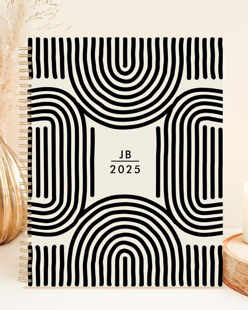 2025 spiral-bound planner with a black and cream abstract design.
