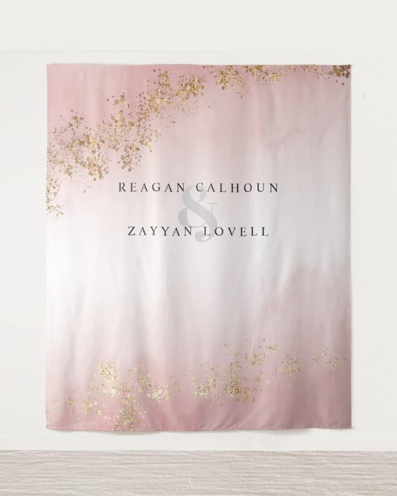 Pink wedding backdrop with gold glitter accents and the names Reagan Calhoun and Zayyan Lovell.