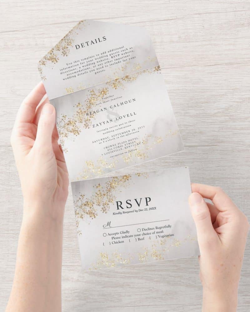 Wedding invitation with gold glitter detail, showing the names Reagan Calhoun and Zayyan Lovell, date, and RSVP information.