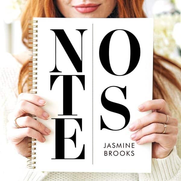 Person Holding A Spiral Notebook With The Word Notes In Large, Bold, Black Lettering On A White Background. The Name Jasmine Brooks Is Printed At The Bottom.