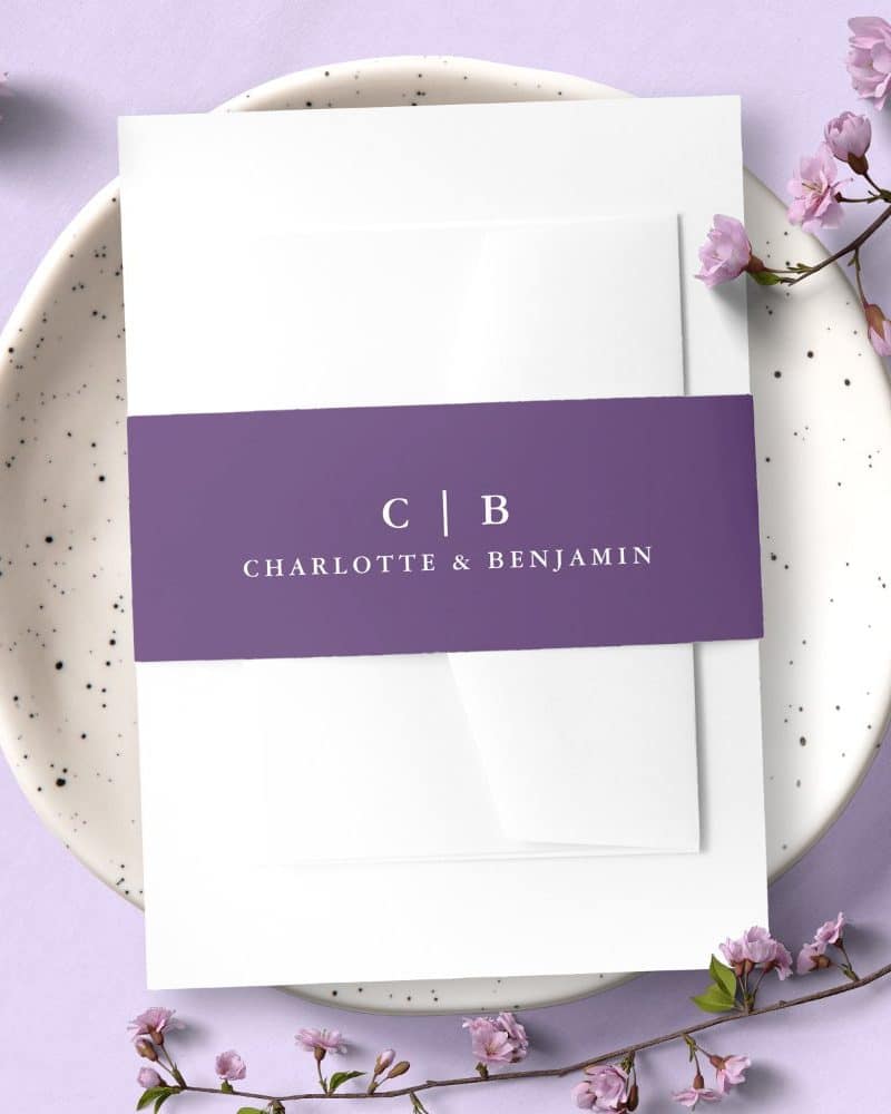 Wedding invitation with a purple band displaying the initials CB and names Charlotte & Benjamin.