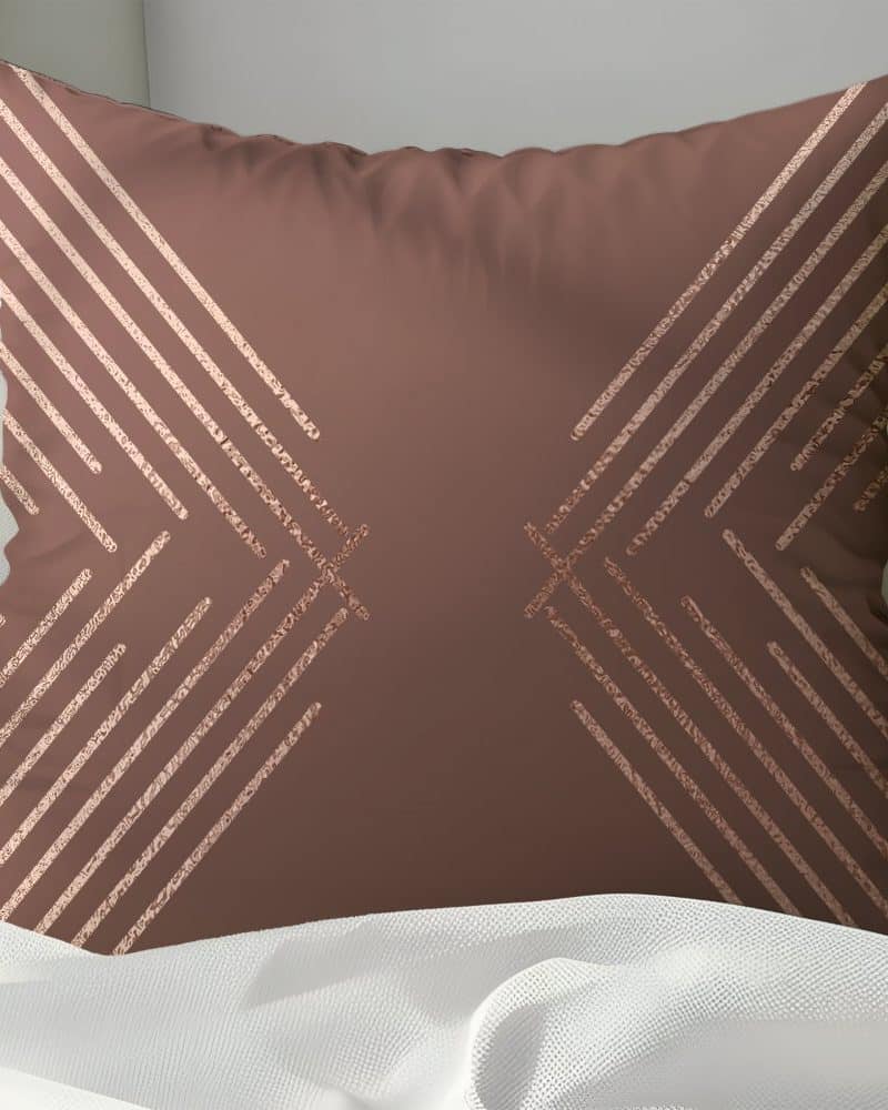 Brown throw pillow with rose gold geometric lines.