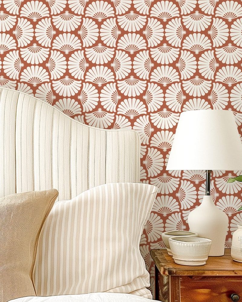 A bed with striped bedding against a wall with a terracotta and off-white floral wallpaper.