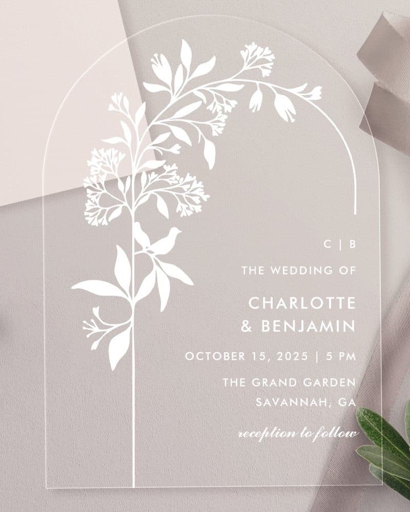 Clear acrylic wedding invitation with a floral design and the names Charlotte and Benjamin.