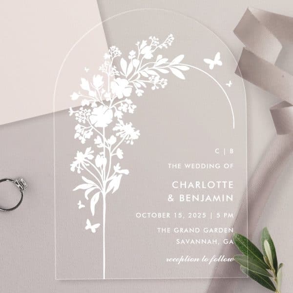 Clear Acrylic Wedding Invitation With A Floral Design And Wedding Details.
