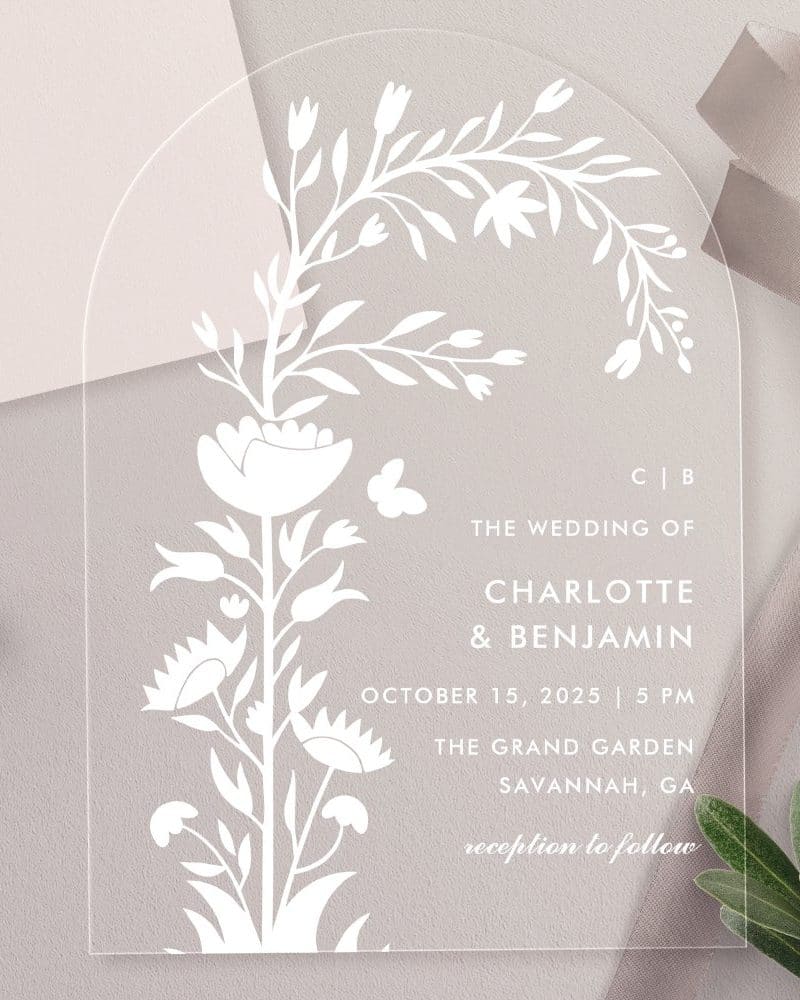 Arch-shaped acrylic wedding invitation with a floral design and the names Charlotte and Benjamin.