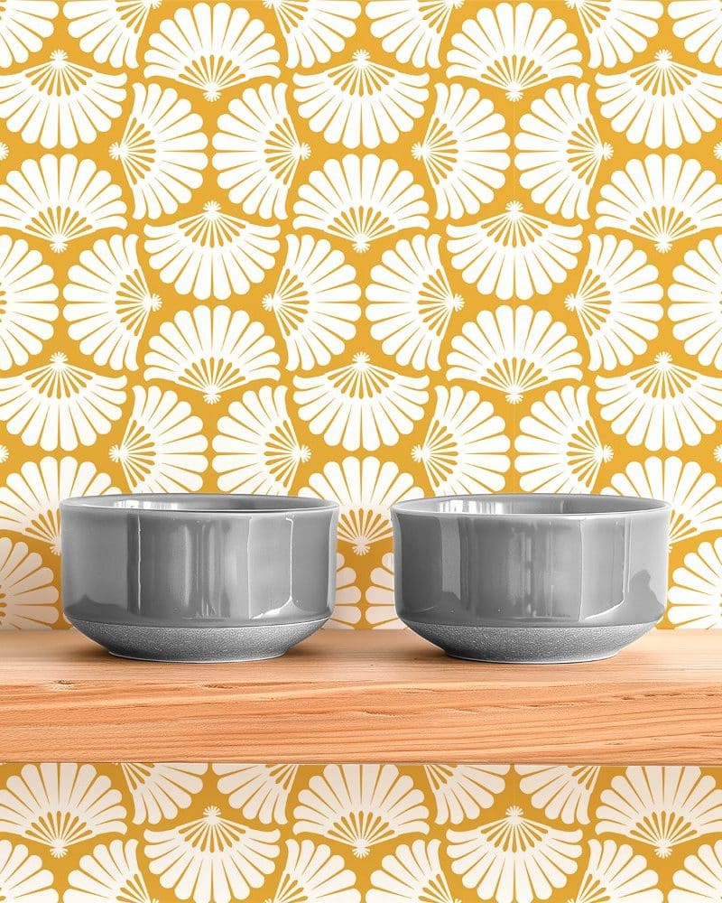 Two gray bowls sit on a wooden shelf against a yellow and white patterned wall.