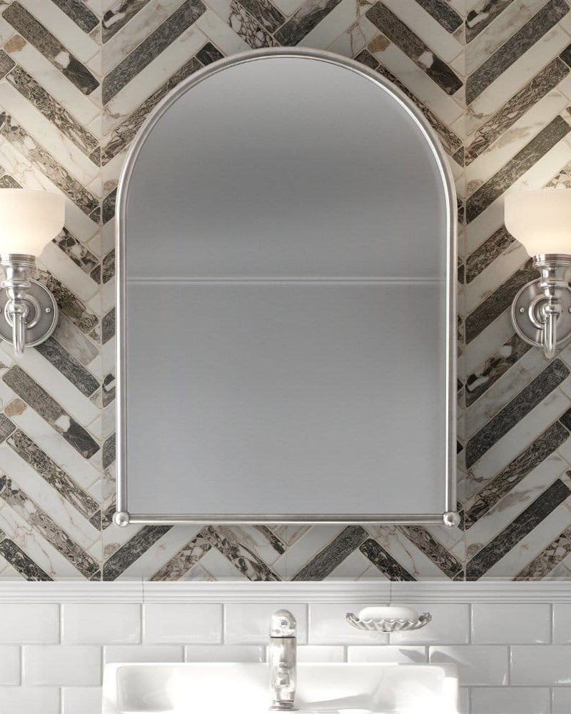 Arched bathroom mirror flanked by wall-mounted lights, above a white subway tile backsplash.