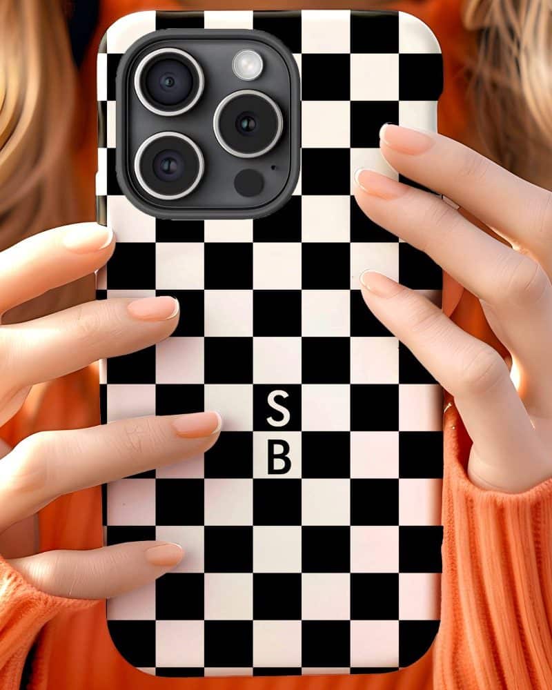 Hands holding a phone in a black and white checkered phone case. The initials SB are in the center.