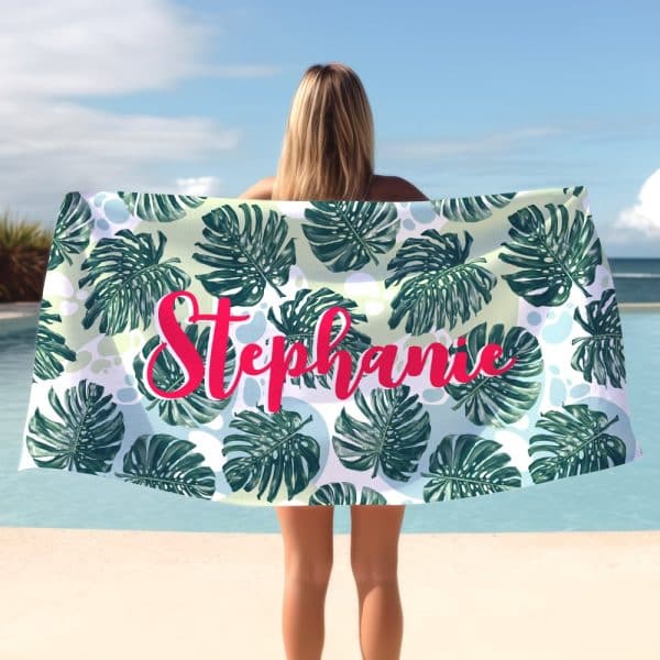 A Woman Holds A Personalized Beach Towel Featuring A Tropical Leaf Pattern And The Name Stephanie.