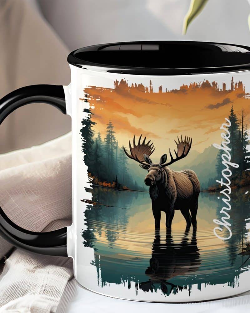 Black-handled mug with a personalized name and illustration of a moose standing in a lake at sunset.