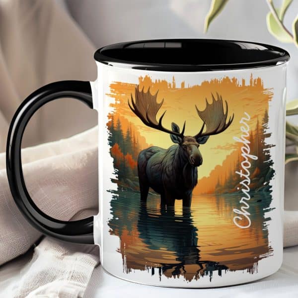 A Coffee Mug With A Black Handle And Rim Features A Detailed Illustration Of A Moose Standing In A Calm Body Of Water At Sunset. The Name Christopher Is Printed On The Mug.