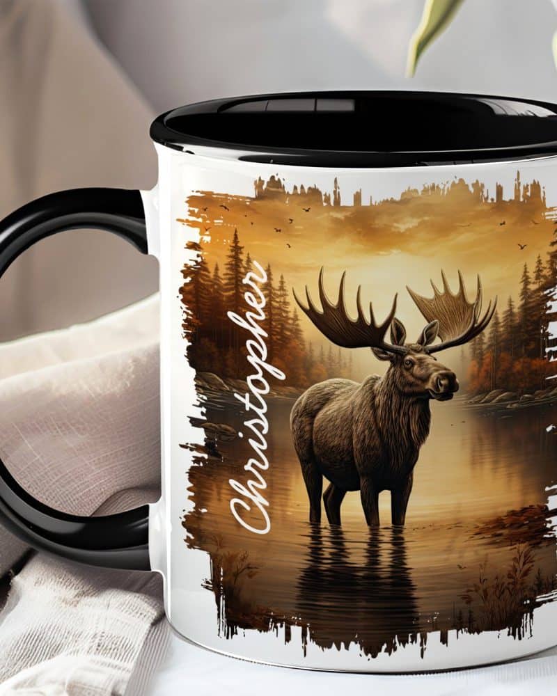 Black-handled mug with a personalized name and image of a moose standing in a lake at sunset.