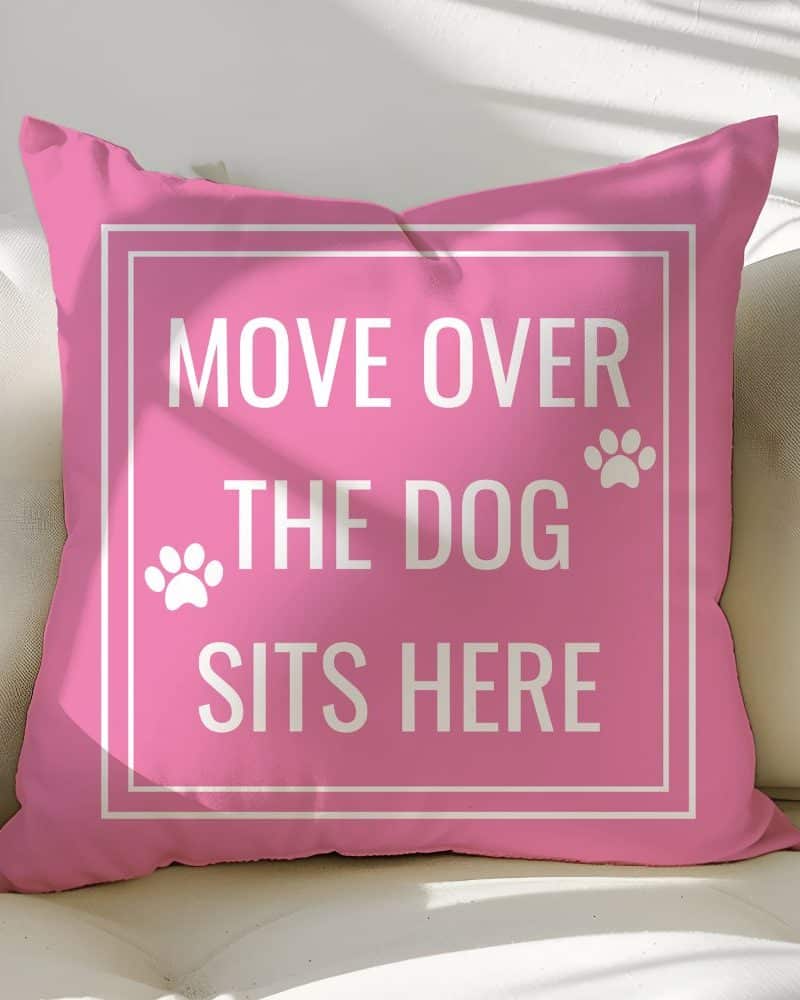 Pink pillow with the text Move Over The Dog Sits Here. Paw prints flank the text.