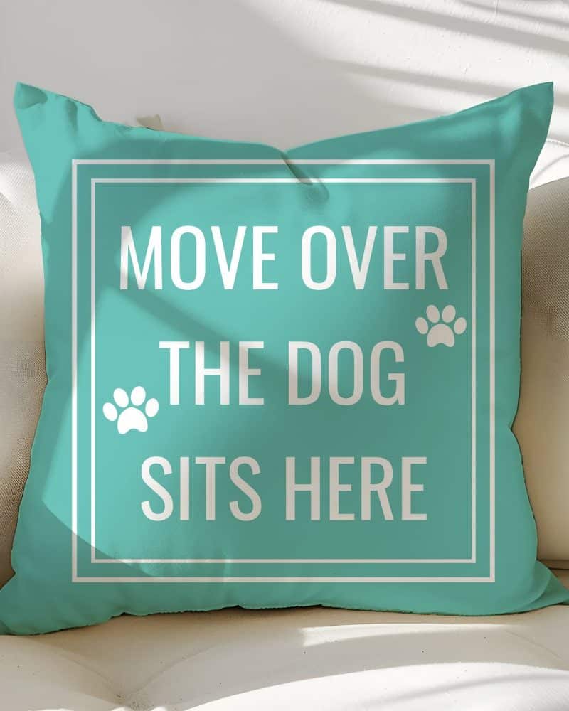 Teal throw pillow with white text reading Move Over The Dog Sits Here and paw prints.