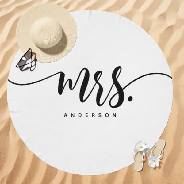 White Round Beach Towel With The Word Mrs. And The Last Name Anderson In Elegant Black Script.
