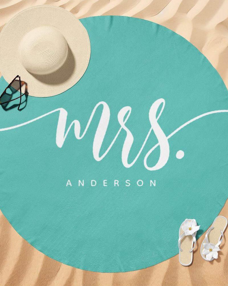 Teal round beach towel with Mrs. Anderson in white script.