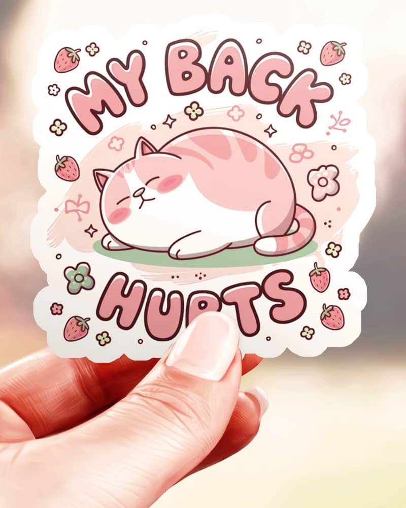 A hand holds a sticker showing a pink chubby cat lying down with the text My Back Hurts.