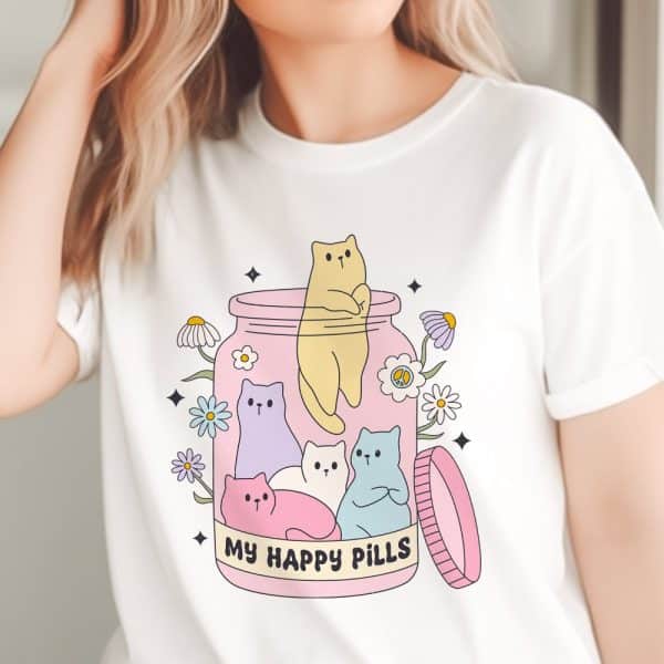 White T-Shirt Featuring A Graphic Of Pastel Colored Cats Inside A Pink Jar, Surrounded By Flowers, With The Text My Happy Pills.