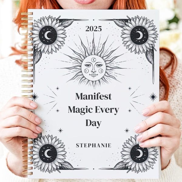 A Person Holds A 2025 Planner Featuring A Sun, Moon, And Sunflowers With The Text Manifest Magic Every Day.