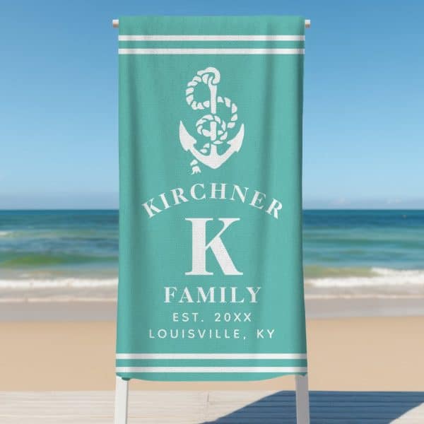 Teal Beach Towel With A White Anchor, The Kirchiner Family Name, A Large K Initial, And Establishment Details.