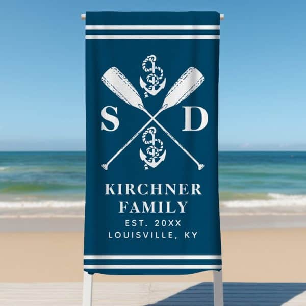 Dark Blue Beach Towel With A White Nautical Design Featuring Crossed Oars, An Anchor, And Family Initials. The Kirchner Family Name And Establishment Date Are Also Included.
