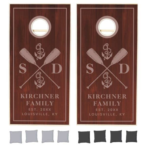 Pair Of Dark Brown Wooden Cornhole Boards, Each Featuring A Nautical Design With Crossed Oars, An Anchor, And Family Initials.