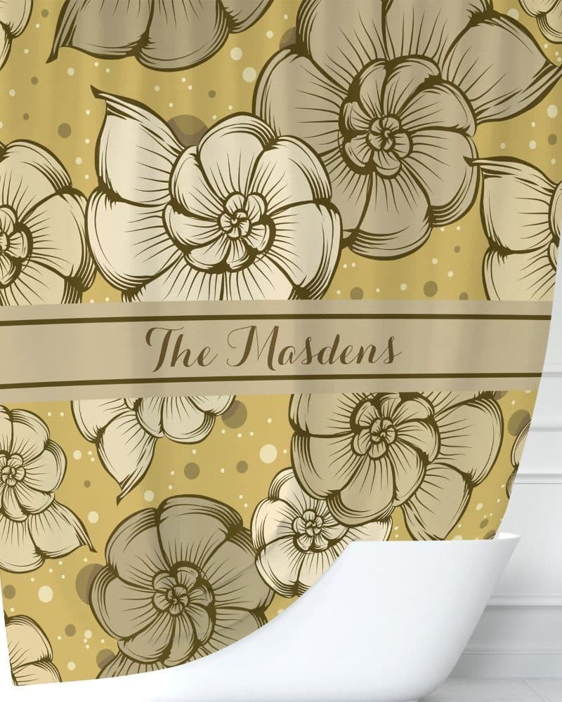 A gold shower curtain with a repeating pattern of stylized flowers and the name The Madsens.